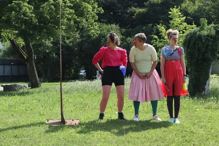 Drei Personen als Clowns verkleidet auf einem Rasen stehend